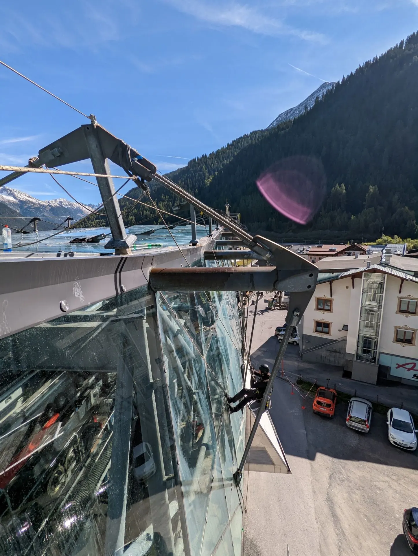 Seilzugang am Glasdach einer Bergbahnstation mit Bergpanorama